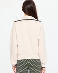 Cream collared cotton jumper and patterned pants by The Upside, KAIRO HALF ZIP KNIT, worn in a relaxed setting.