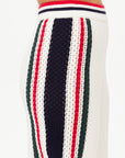 Close-up of a knitted garment in organic cotton, featuring vertical stripes in red, navy blue, and green on a white background. The fabric exhibits a textured pattern, with the waistband adorned with red and navy blue stripes. Perfectly paired with the Reverie Kansas Pant from The Upside for a casual yet stylish look.