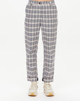 A person wearing The Upside's Highlands Pant, featuring a black and white checkered design, combined with white sneakers. Made from organic cotton, these pants provide comfort with their elastic waistband, set against a plain white background.