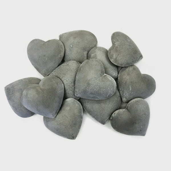 A collection of Zinc Heart stones from Sugarboo Designs rests gracefully on a white background, ideal for adding rustic charm to any home décor.