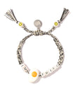 Venessa Arizaga's Bracelet 6" is a quirky black-and-white braided charm bracelet with “IM FRIED” beads, a fried egg charm, yellow smiley face beads, playful tassels, and a fun junk food-inspired vibe.