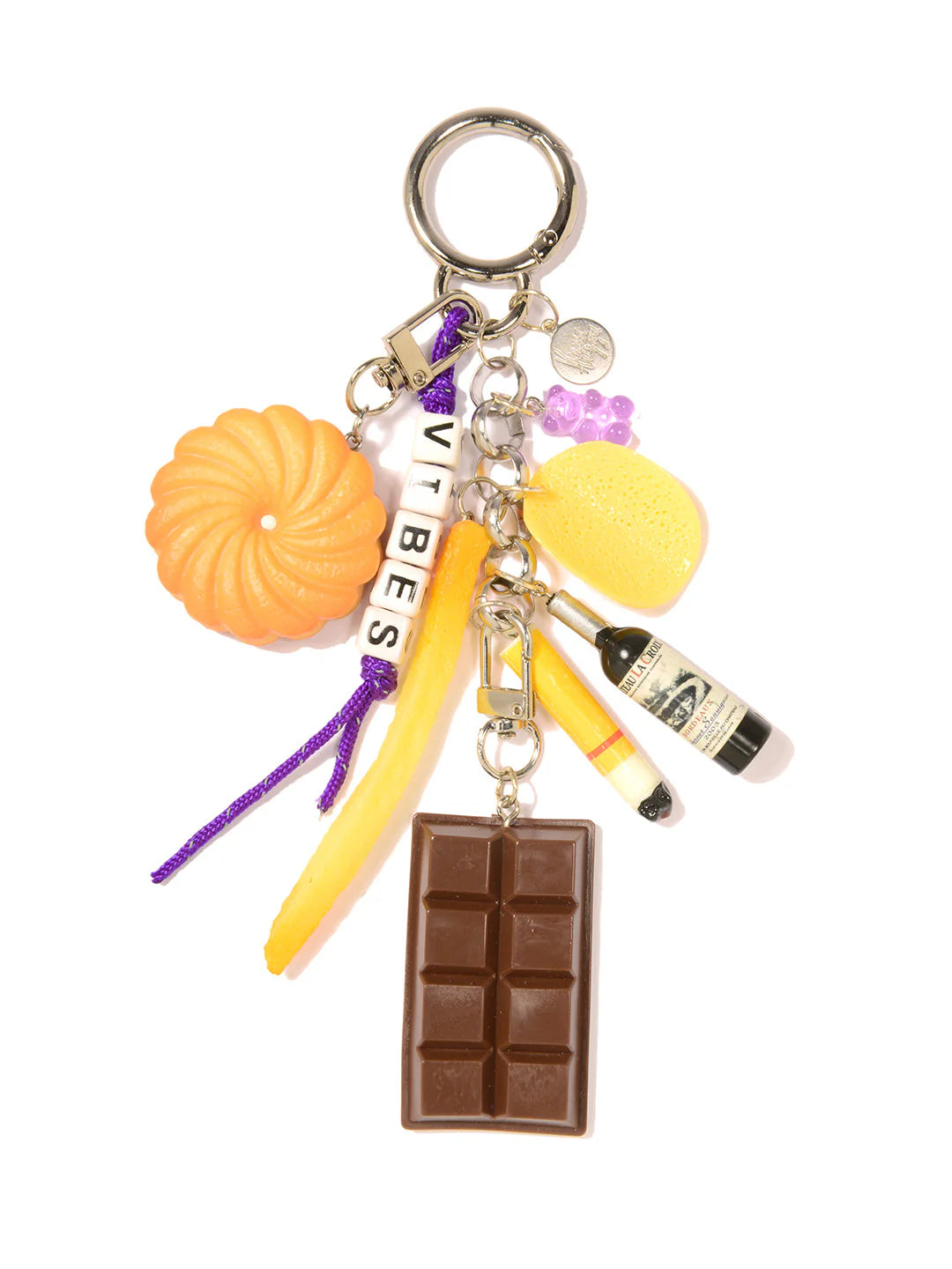 The Venessa Arizaga Bag Key Leash features playful food charms—a chocolate bar, bundt cake, yellow fry—plus a yellow sponge, bottle, purple beads, and &quot;VIBES&quot; letter beads on a silver keyring. Fun as a whimsical bag charm!.