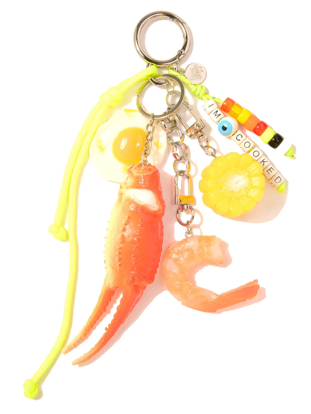The Bag Key Leash by Venessa Arizaga features food charms—sunny-side-up egg, crab claw, corn, shrimp—and colorful "IM COOKED" beads on a neon yellow cord with metal rings. A fun and unique bag charm!.