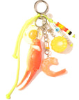 The Bag Key Leash by Venessa Arizaga features food charms—sunny-side-up egg, crab claw, corn, shrimp—and colorful "IM COOKED" beads on a neon yellow cord with metal rings. A fun and unique bag charm!.