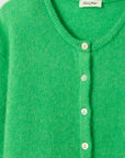 A close-up of the Vitow Cardigan by American Vintage, crafted from premium knitwear in green. It features a round neckline, five light-colored buttons, and a small white label sewn into the collar.