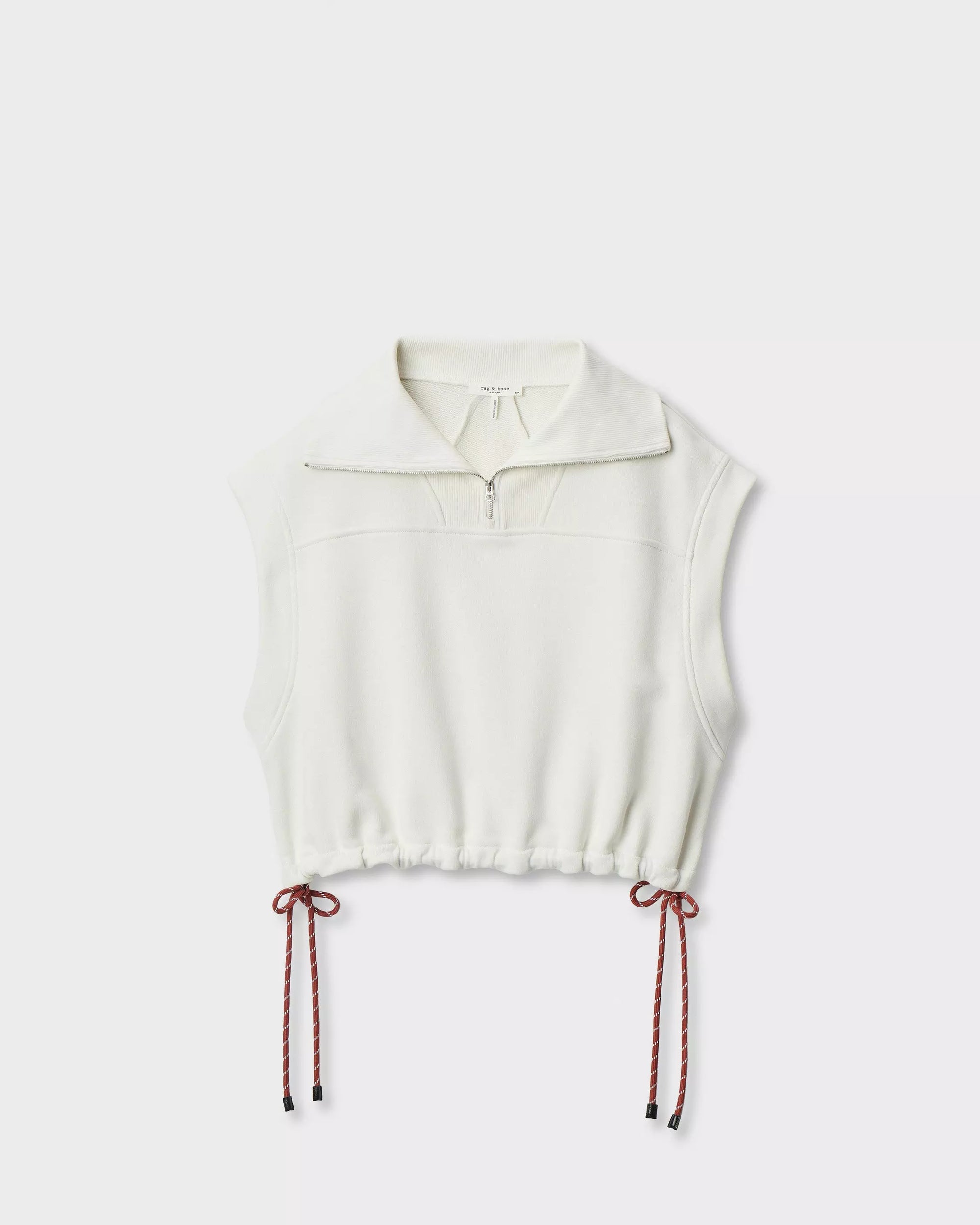 The Rag & Bone vintage terry half zip muscle is a sleeveless white cotton-blend pullover with a half-zip collar, drawstring hem, and red side cords in bows, giving it a subtle vintage vibe against a clean background.