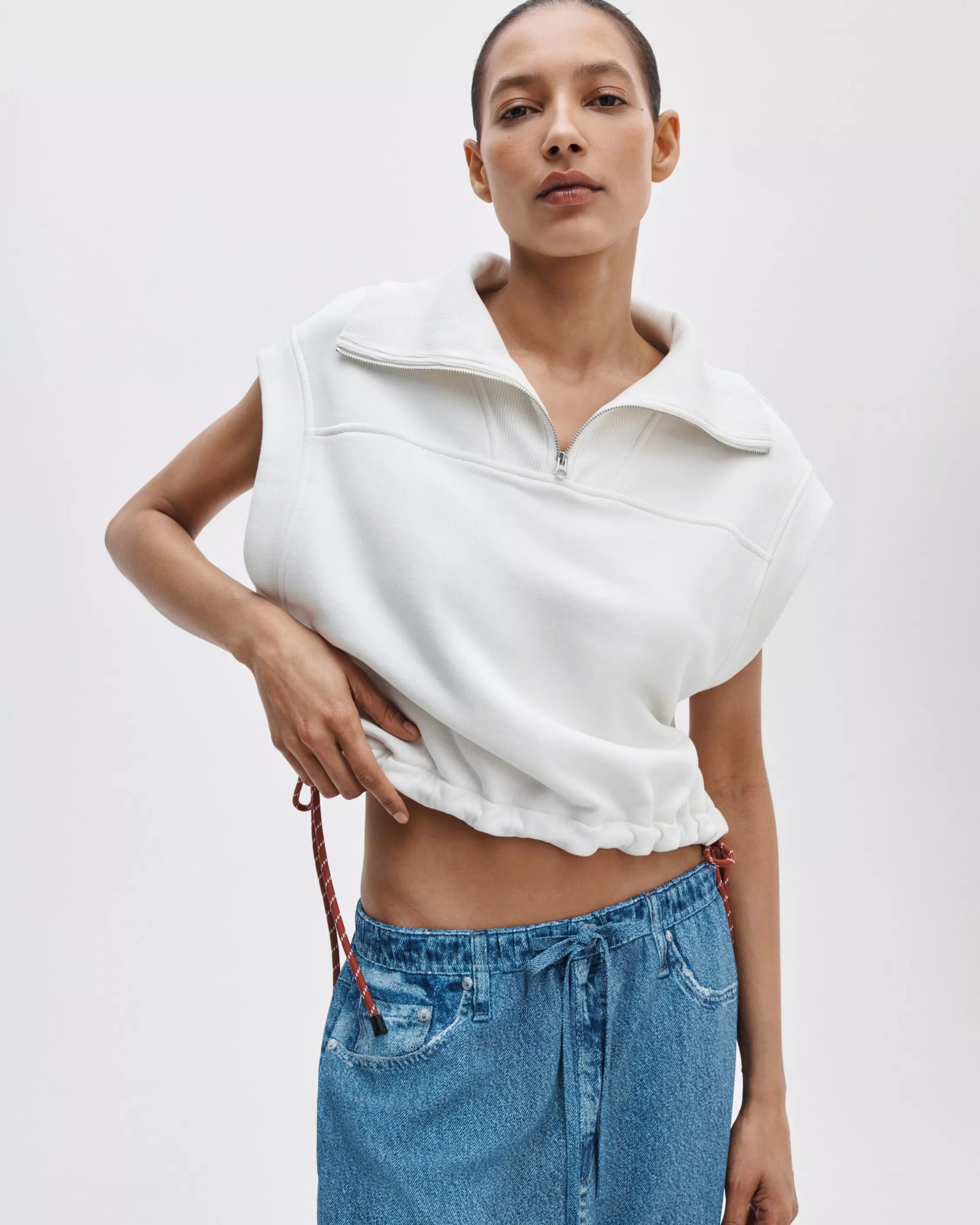 Wearing the Rag & Bone vintage terry half zip muscle with a drawstring hem and blue drawstring denim pants, a person adjusts the waistband while posing against a plain light background.