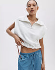Wearing the Rag & Bone vintage terry half zip muscle with a drawstring hem and blue drawstring denim pants, a person adjusts the waistband while posing against a plain light background.