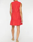 A person faces away from the camera wearing the VIOLA DRESS by BROCHU WALKER, a sleeveless, knee-length feminine dress with ruffle details, paired with beige flat shoes on a plain white background.
