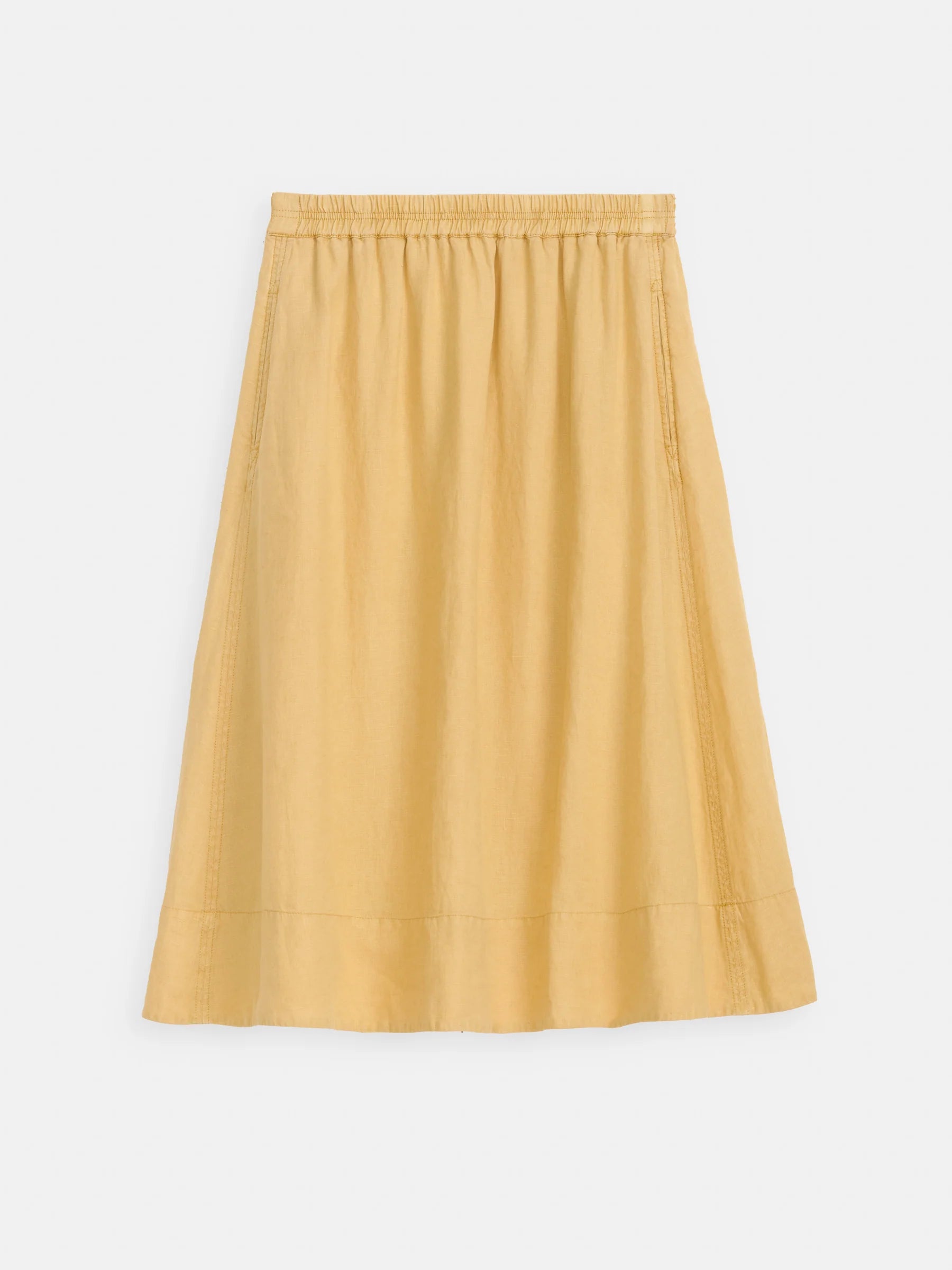 The Alex Mill Maddie Skirt Linen is a knee-length, A-line linen skirt in light mustard yellow with an elastic waistband, seam details, and pockets; garment-dyed for a textured look—shown on a white background.