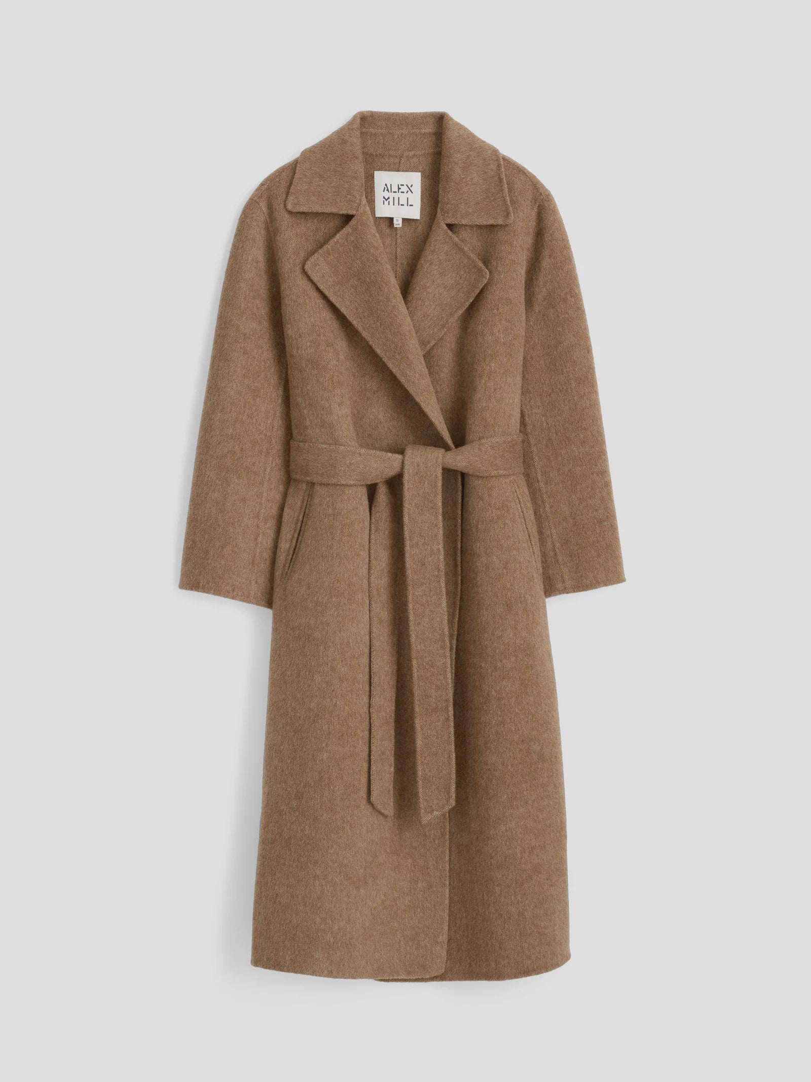 A full-length, brown vintage overcoat crafted from wool, known as the Georgia Wrap Coat, features a wide collar and a matching belt cinched at the waist. Its tailored design includes long sleeves, displayed elegantly against a plain white background. The label inside reads "Alex Mill.