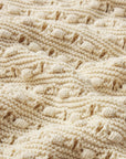 Close-up of The Bauble Skirt by FRAME, showcasing cream-colored knitted fabric with raised cables and bobbles for a cozy, textured, and intricately designed look.