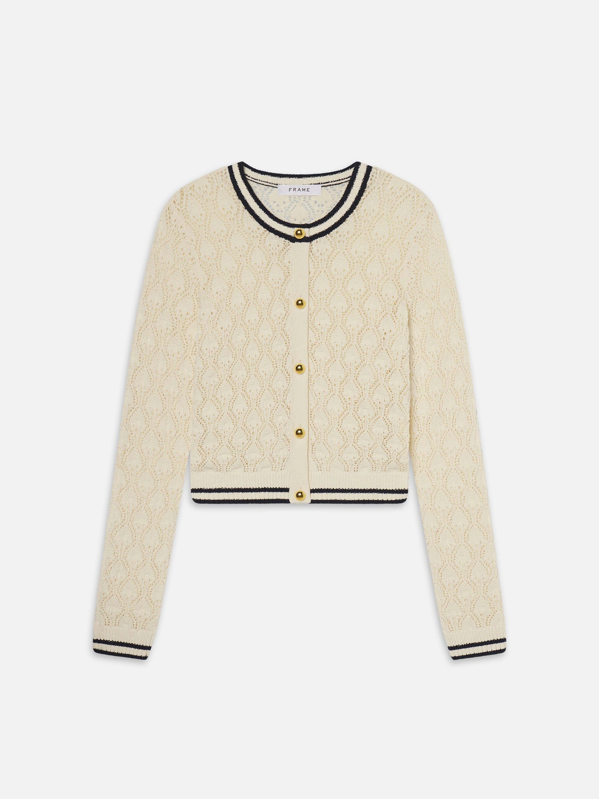 The FRAME The Rookie Cardi is a cream long-sleeve cardigan in lightweight knit with a diamond openwork texture, gold buttons, and black striped trim on the round neck, cuffs, and hem.