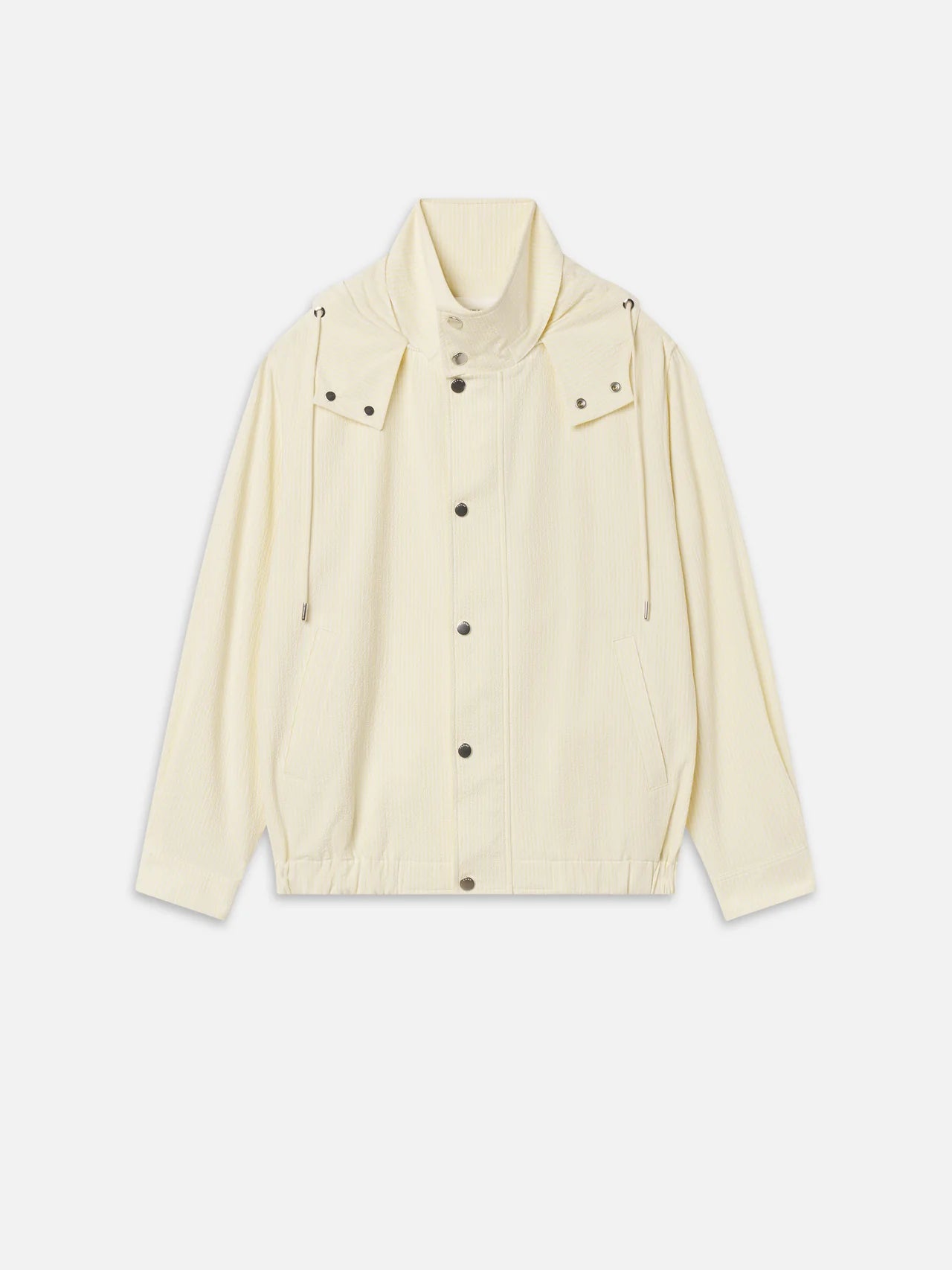 The Seersucker Track Jacket by FRAME is a cream long-sleeve seersucker jacket with snap buttons, front pockets, high collar, adjustable drawstrings, and an elasticated hem, shown on a white background.