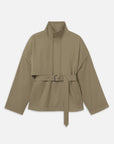 The Short Field Trench by FRAME is a khaki trench with a high collar, wide sleeves, front flap detail, two pockets, and a matching fabric belt with metallic eyelets and rectangular buckle—perfect for transitional layering.