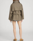 A person faces away, wearing FRAME's The Short Field Trench with denim shorts and tan flats—demonstrating effortless transitional layering against a plain white background.