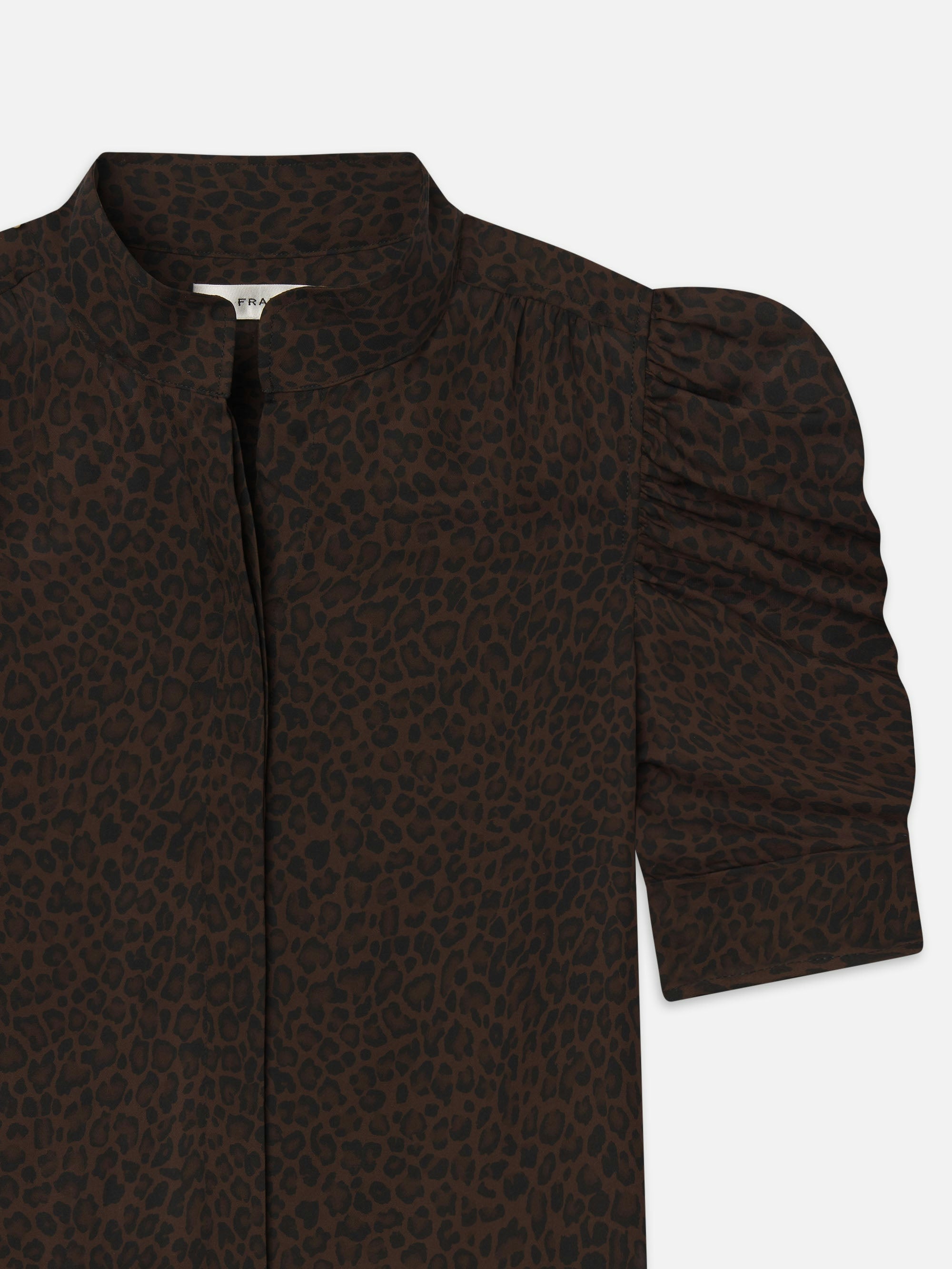 A close-up of The Leopard Gillian Top by FRAME, showcasing its silk fabric, puffed sleeves, and high neckline.