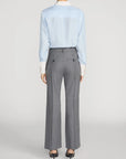 Striped silk shirt by FRAME styled with gray dress pants and black heels, back view.