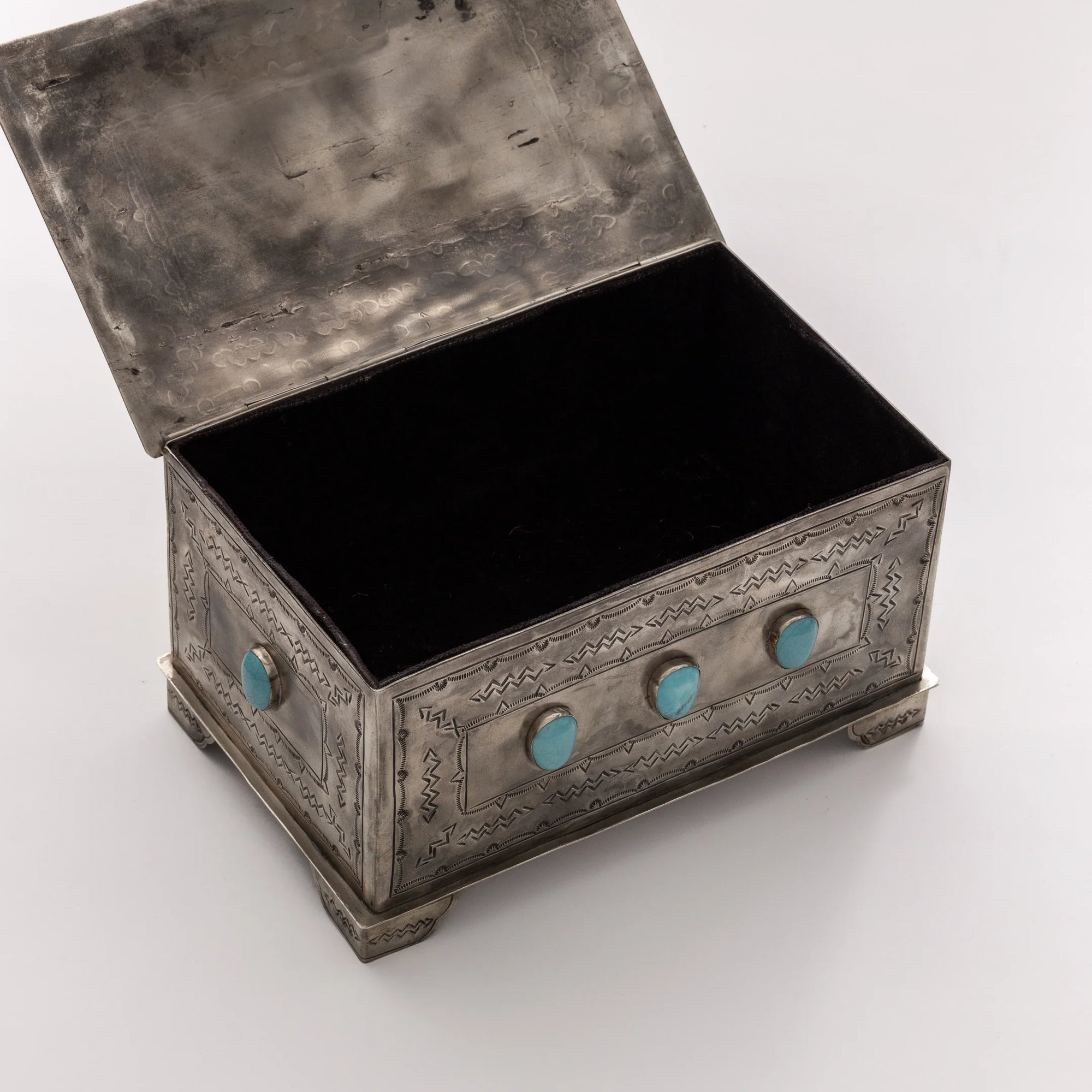 The J Alexander Rustic Silver 9 Stone Turq Box is a rectangular rustic silver box with an open lid, engraved patterns, and nine turquoise stones on the side, set on ornate feet—an ideal Southwestern decor accent shown against a white background.