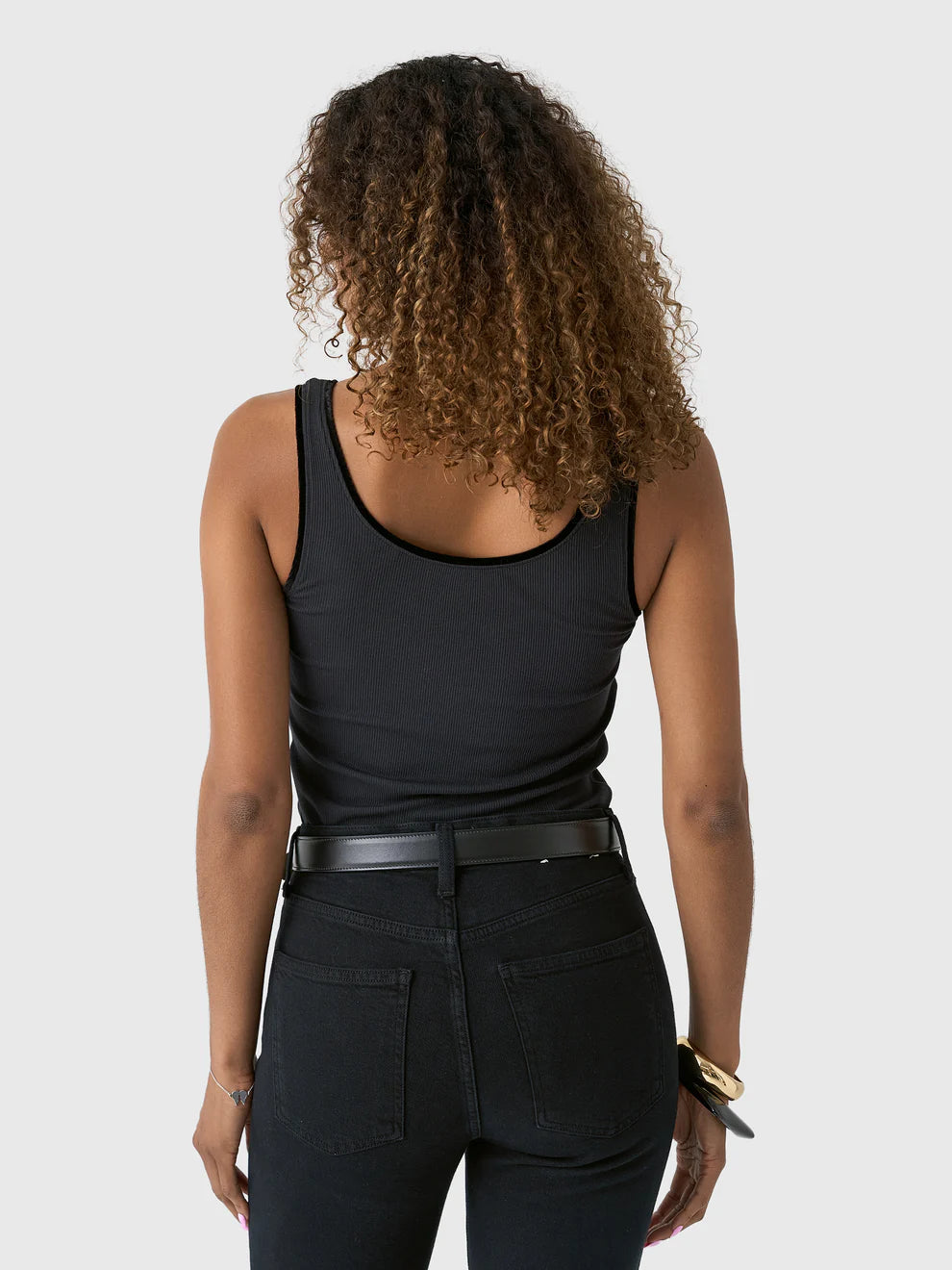 A person with curly hair wears the FRAME Velvet Trim Tank, black jeans, and a black belt, shown from the back against a light gray background—an easy, layered look.