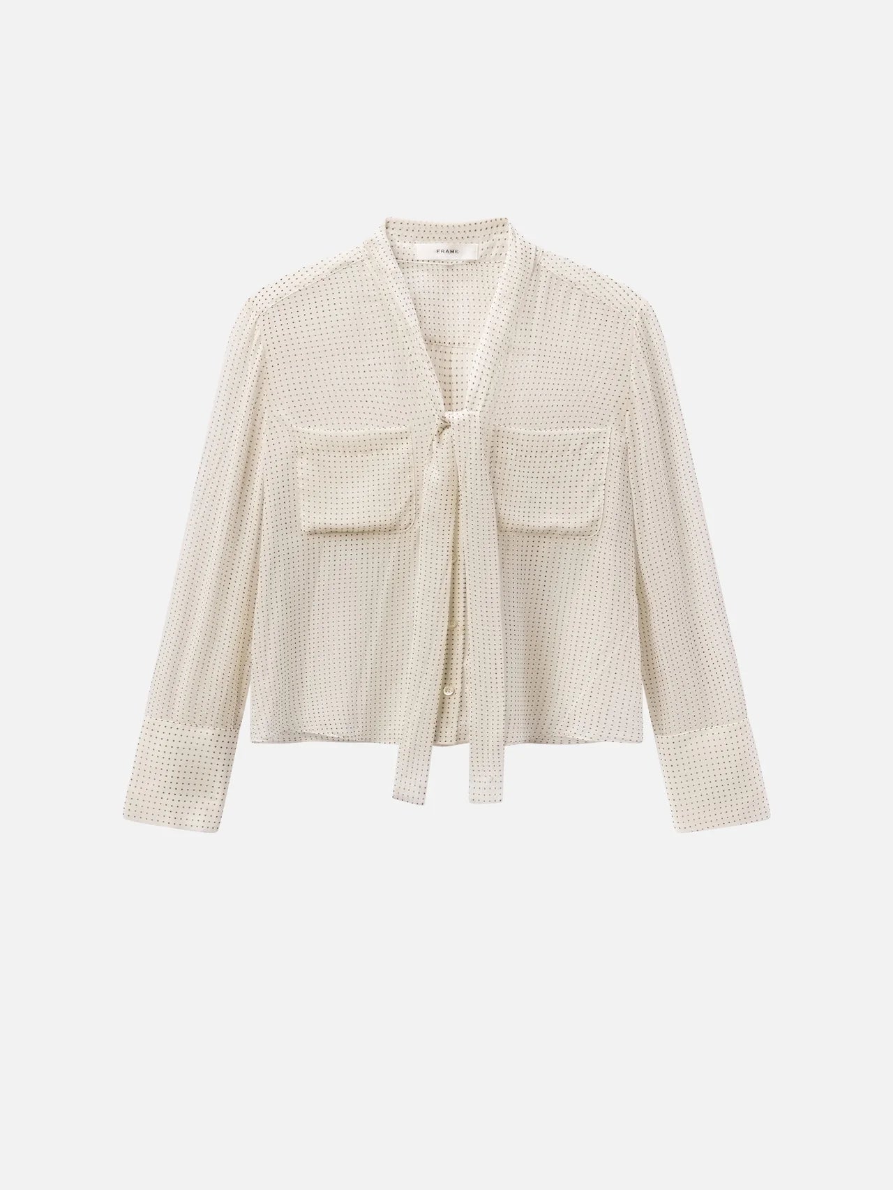 The FRAME Polka Dot Modern Tie Blouse is a cream-colored, long-sleeve top with a tie-front neckline, two chest pockets, and a textured mesh-like pattern, shown on a plain white background.