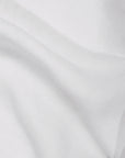 A close-up of the Matteo Tat Cotton Sham highlights its smooth, slightly translucent white fabric with gentle folds, subtle shadows, and a crisp percale weave.