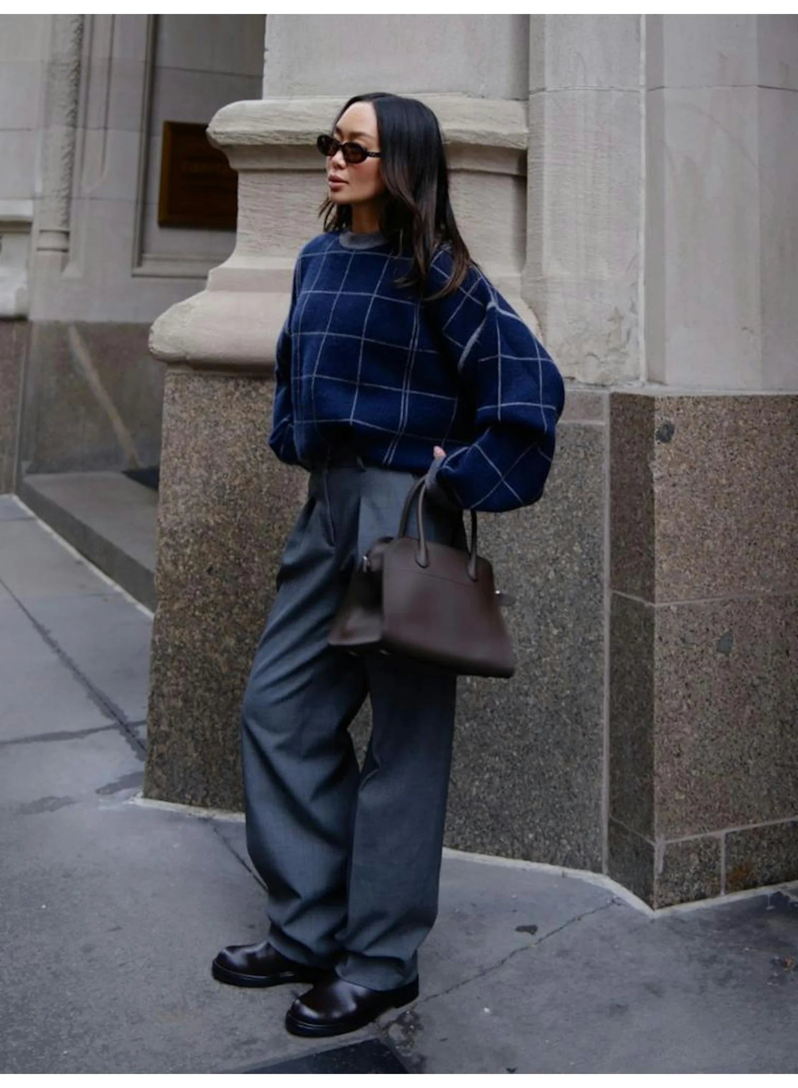 White + Warren cashmere windowpane sweatshirt styled with gray trousers and brown bag outside a stone building.