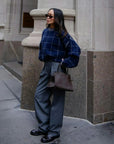 White + Warren cashmere windowpane sweatshirt styled with gray trousers and brown bag outside a stone building.