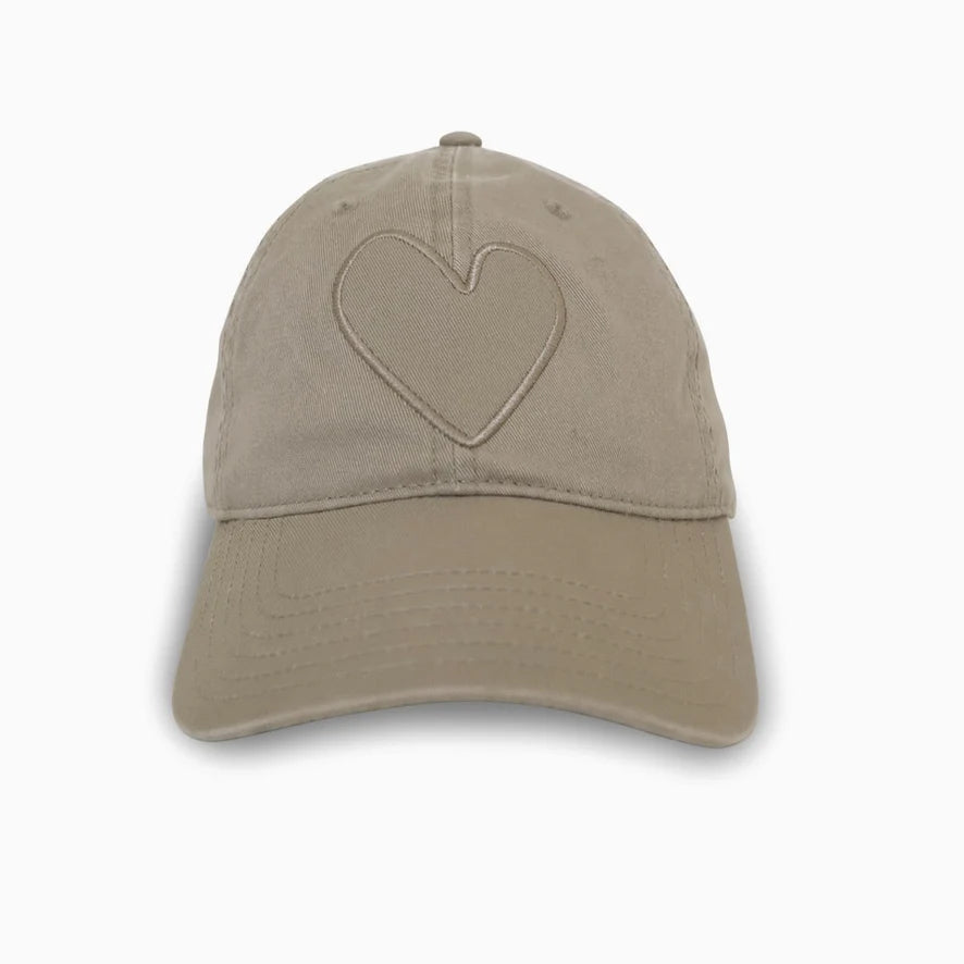 The Imperfect Heart Hat by Kerri Rosenthal is a beige baseball cap made from stone-washed cotton, featuring an Imperfect Heart patch on the front. Its white background highlights the cap's simple and minimalist design.