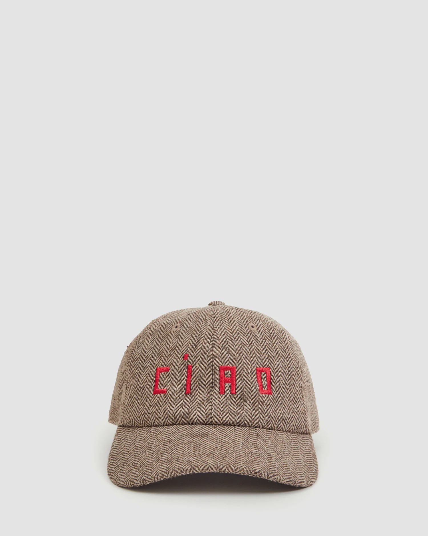 The Clare Vivier Wool CIAO Baseball Hat features a brown herringbone pattern, Peaky Blinders inspiration, and "CIAO" embroidered in red on the front, shown against a plain light background.