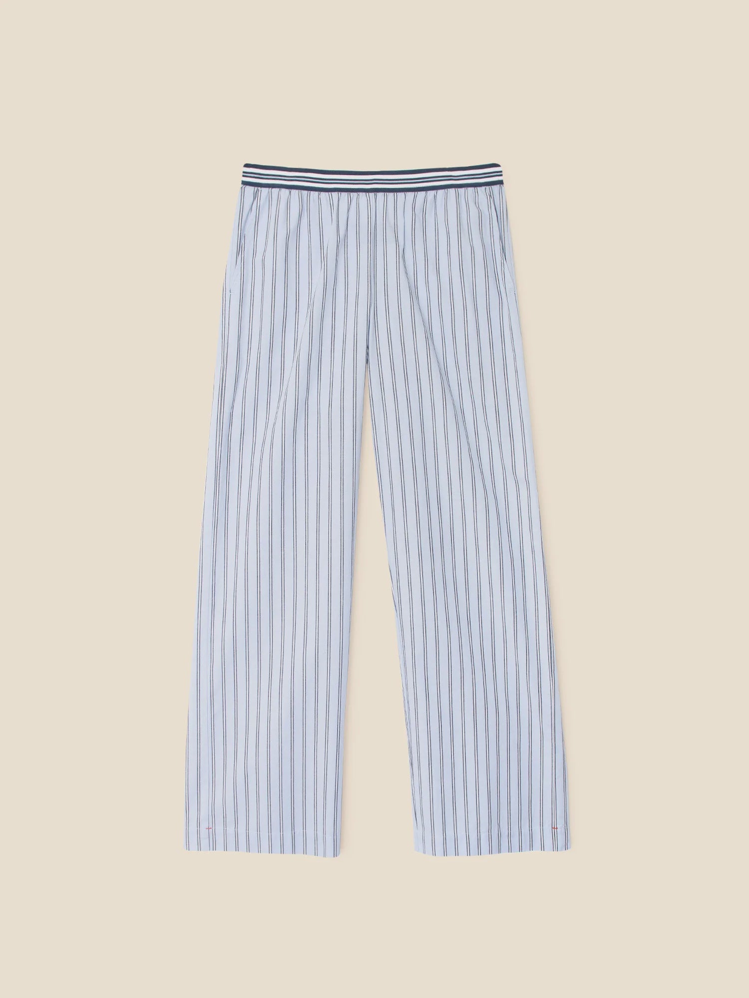 The Alto Pants by Xirena are light blue striped pants with dark vertical lines and an elastic waistband featuring navy and white stripes, shown laid flat on beige. Style them with a cascade stripe shirt for a chic, relaxed look.