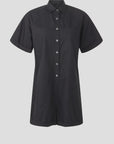 The Franklin Romper by Xirena is a black, short-sleeved, button-up romper with a collar, front patch pockets, and a relaxed utility fit, shown against a plain light gray background.