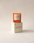 The Nosedive Candle by Faire, a vegan orange soy candle labeled "YES/NO/MAYBE," sits on its matching white box against a light background. Enjoy its rich Smoky Woody scent, inspired by Mixtape 1999.