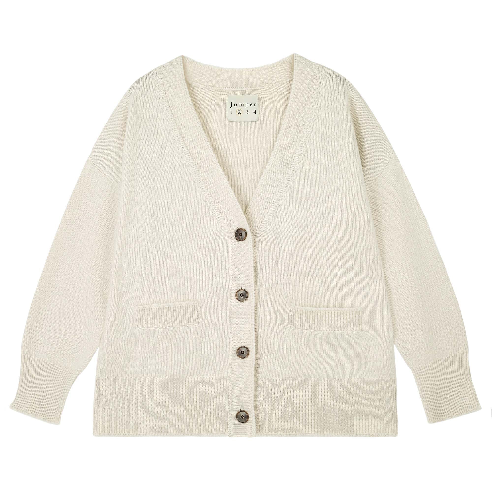 The Boyfriend Heavy Cardigan by Jumper 1 2 3 4/CR2 is a cream cashmere knit with an oversized fit, long sleeves, two front pockets, ribbed cuffs and hem, and a V-neckline with four brown buttons.