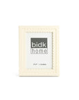 The BIDK Home 5x7 Floral Resin Frame features a cream hue and scalloped edge, made from premium resin. Displayed upright with a "bidk home" placeholder image, it's perfect for adding elegance to any home decor.