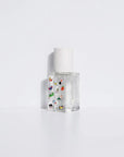 The Maison Matine Perfume by Faire features a clear glass bottle with a white speckled cap, adorned with colorful stickers of objects and animals, and hints at notes of bergamot and musk, displayed on a plain white background.