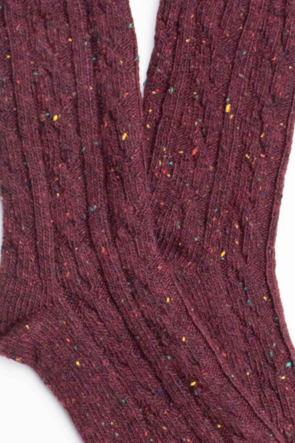Close-up of Faire Wool Speckled Knit Socks in maroon, with a ribbed cable-knit design and yellow, blue, and red speckles throughout the wool-blend fabric.
