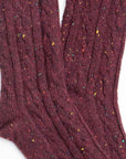 Close-up of Faire Wool Speckled Knit Socks in maroon, with a ribbed cable-knit design and yellow, blue, and red speckles throughout the wool-blend fabric.