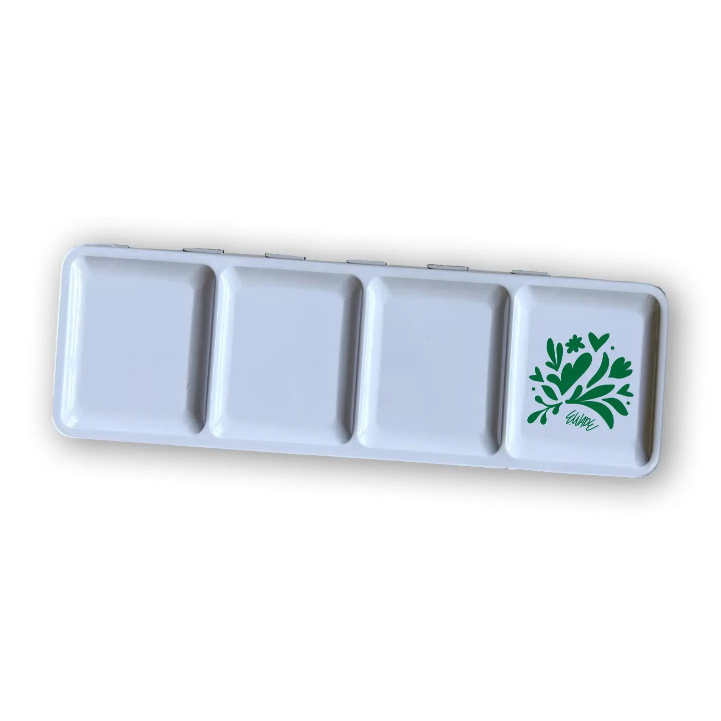 The Faire Watercolor Paint Set w/ Brush features a rectangular white palette with four square wells, the last decorated with a green floral and leaf design accented by small hearts.