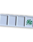 The Faire Watercolor Paint Set w/ Brush features a rectangular white palette with four square wells, the last decorated with a green floral and leaf design accented by small hearts.