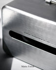 A close-up of the Faire Paper Towel Wall Case shows its aluminium body with a matte finish, a horizontal slot, and subtle registration details. "Matte Finish" is printed below this stylish storage container.