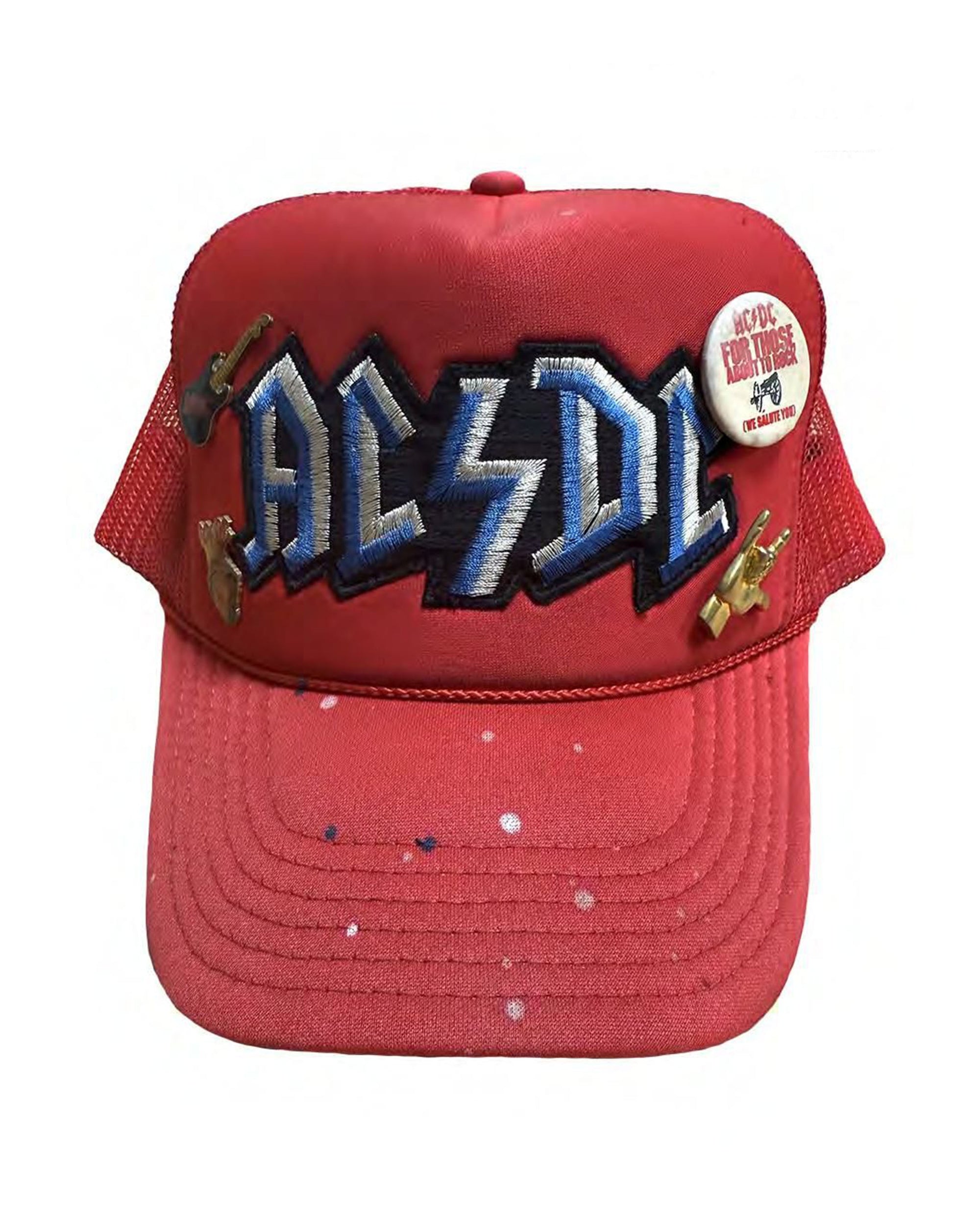 The Made Worn AC/DC Hat features a bold red design with the blue and white logo, small guitar pins, a "For Those About to Rock 1981-1982" button on the right, and white paint splatters for added classic rock flair.