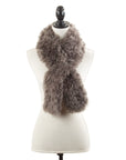 The Faire Lamb Fur Pull Through scarf, in light brown, is shown draped around a white dress form mannequin with a black finial, set against a plain white background to highlight its luxurious warmth and style.