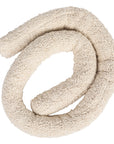 The Bloomingville Cotton Knotted Pillow is a soft, textured cream decorative cushion crafted from coiled fabric, arranged in a loose spiral and resembling a plush draft stopper or stuffed snake.