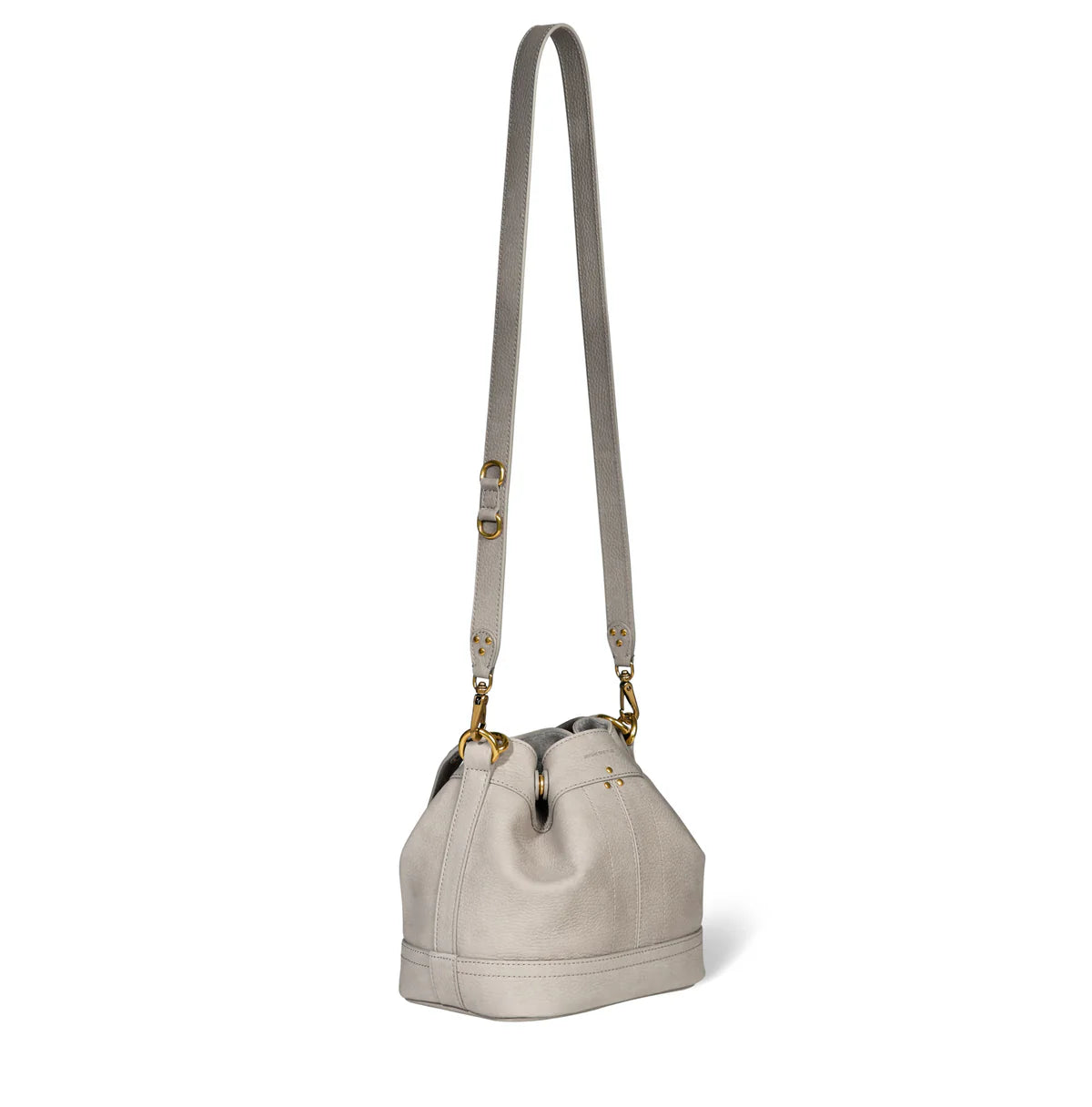 The Ben Small Bucket by Jerome Dreyfuss is a luxurious calfskin bucket bag in light gray, featuring a long leather shoulder strap, gold hardware, and a drawstring closure with a simple, elegant design.