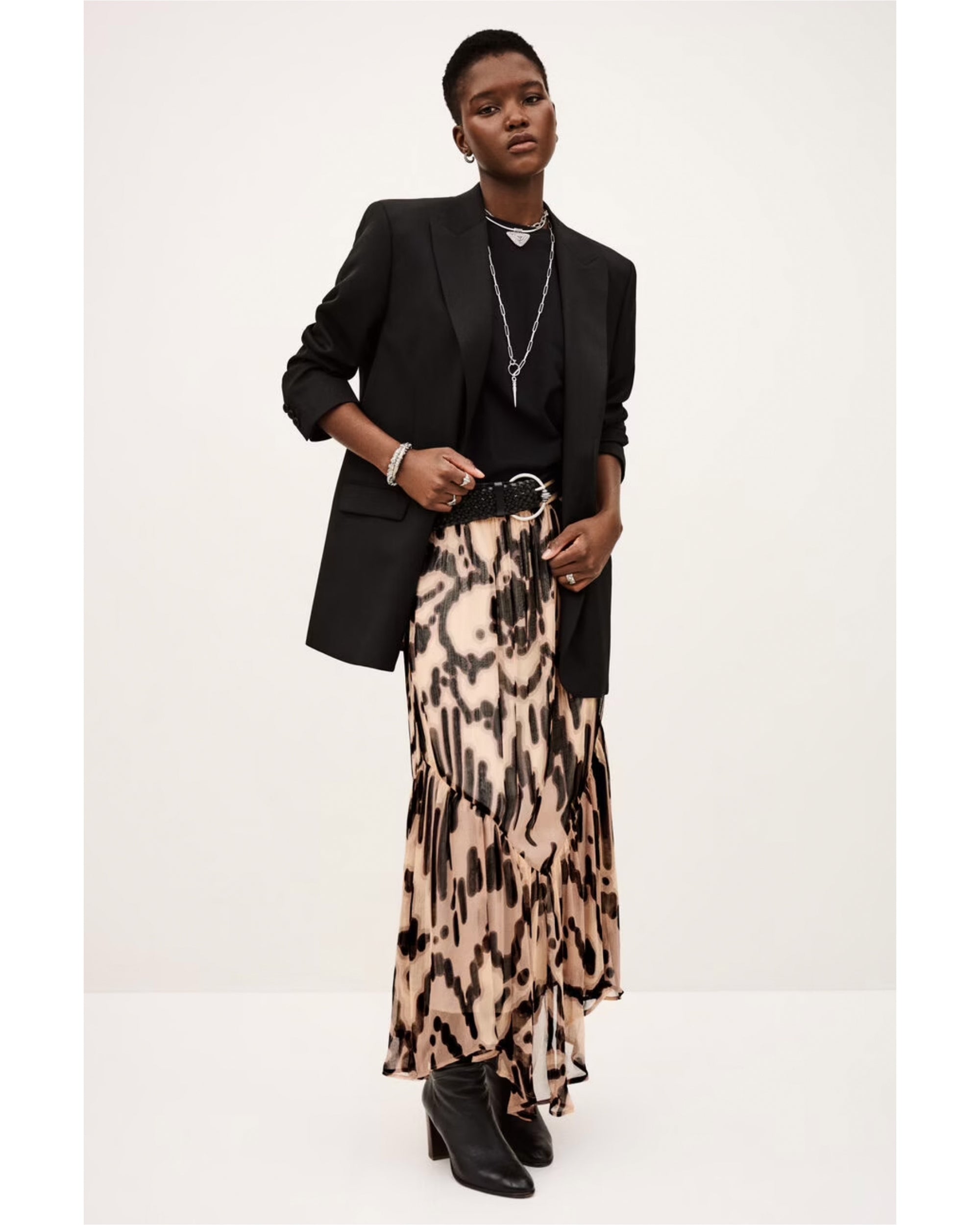 A person models the BA&SH Skirt Aley, paired with a black blazer, black top, boots, and silver jewelry, posing confidently against a plain light background.