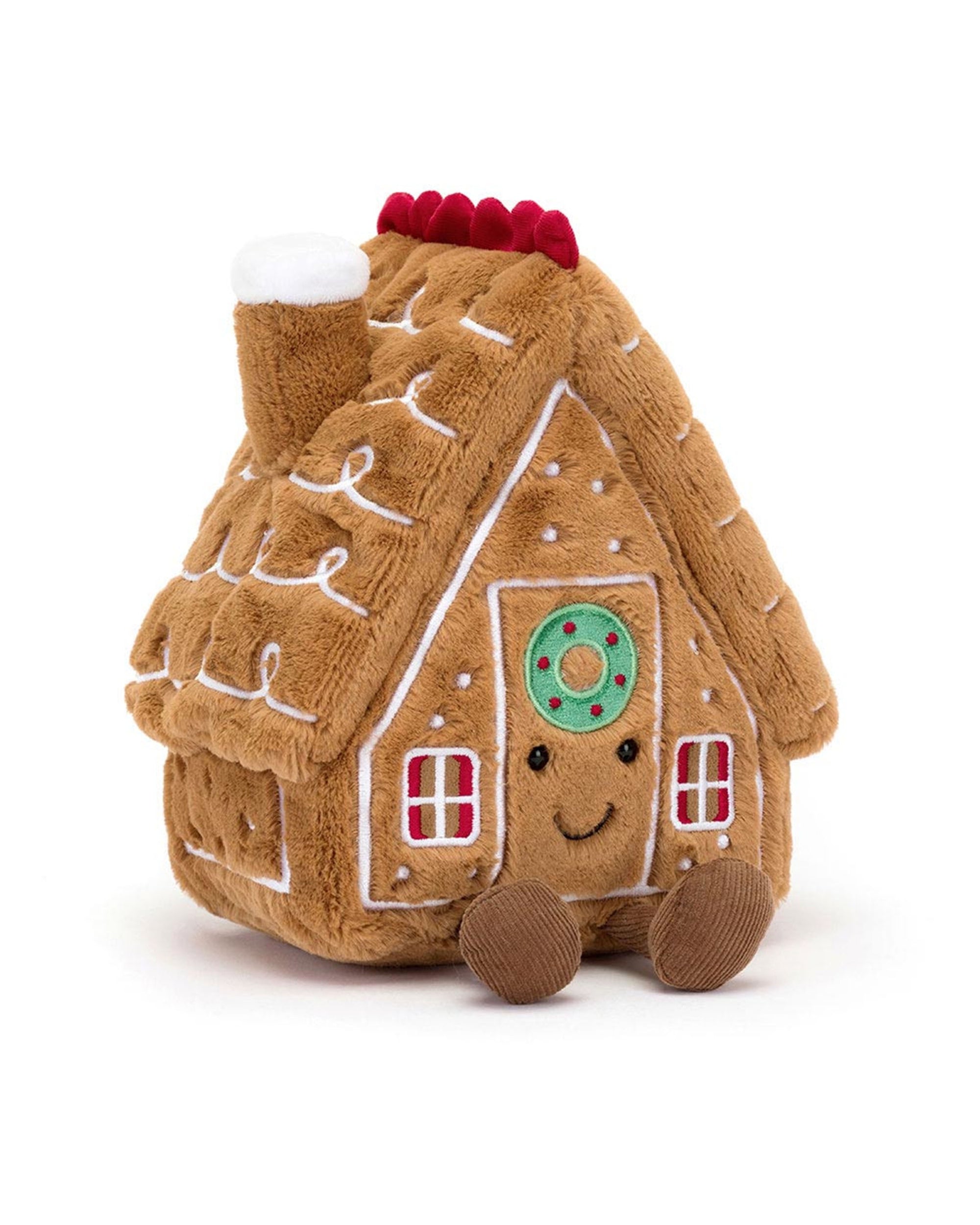 The Amuseables Gingerbread House by Jelly Cat Inc. is a soft, plush toy with white icing details, red windows, a smiling face, and brown feet. Its roof features a chimney topped with white icing and red accents.