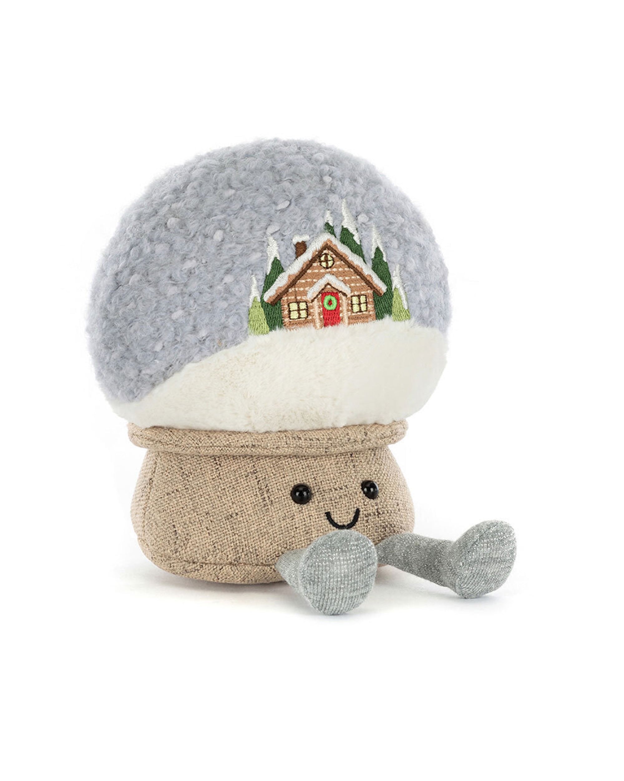 The Jelly Cat Inc. Amuseables Snow Globe is a plush toy featuring a smiling face, gray arms and legs, and a fuzzy round top embroidered with a snowy cabin, trees, and après ski scene.