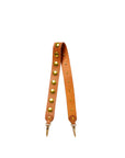 The Anse Festival Strap by Jerome Dreyfuss features genuine vegetable-tanned cowskin in tan, adorned with large gold metal studs and secure clasps at both ends, shown on a plain white background.
