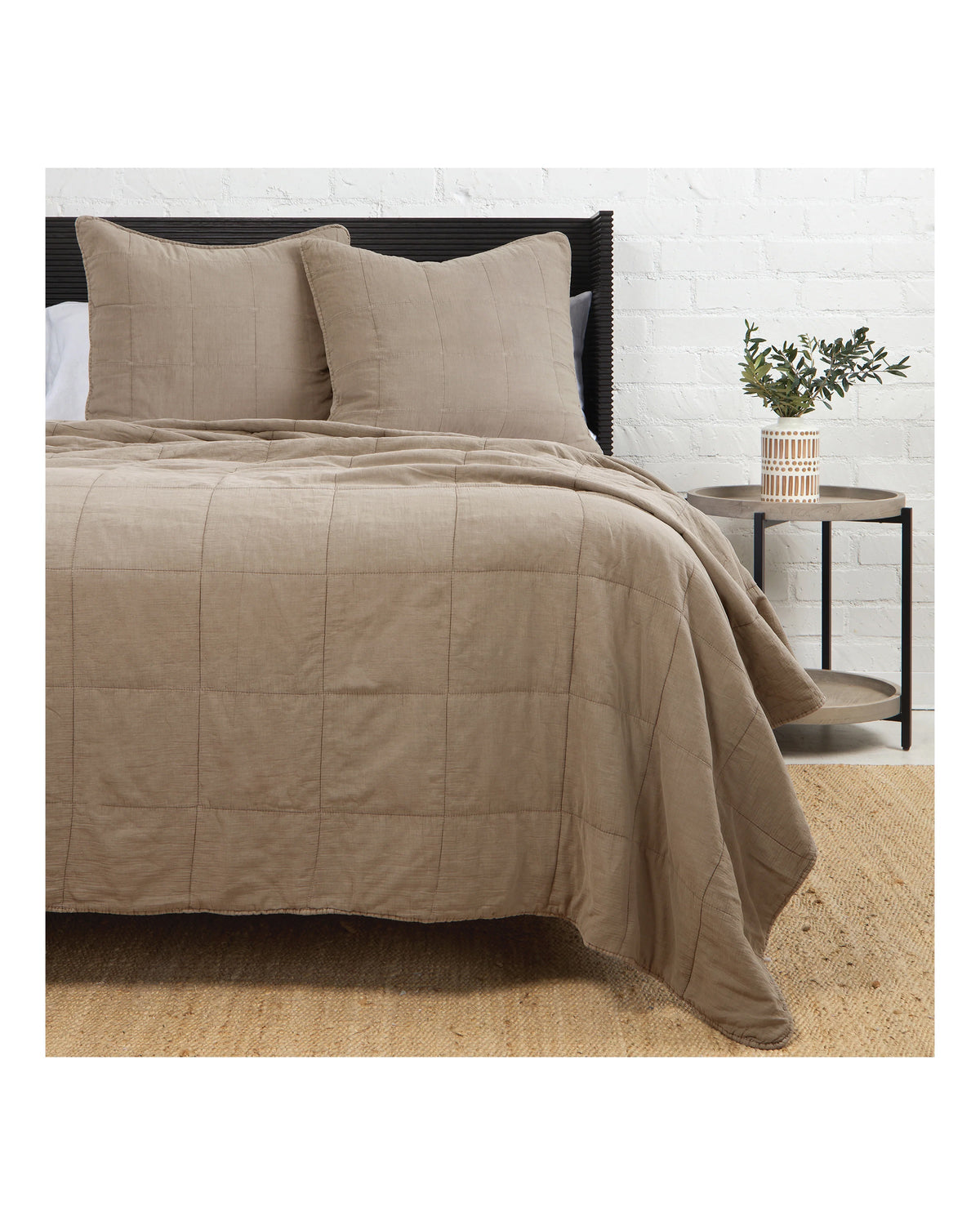 King-size Antwerp coverlet with matching pillows by Pom Pom on a bed beside a round table with a small plant.